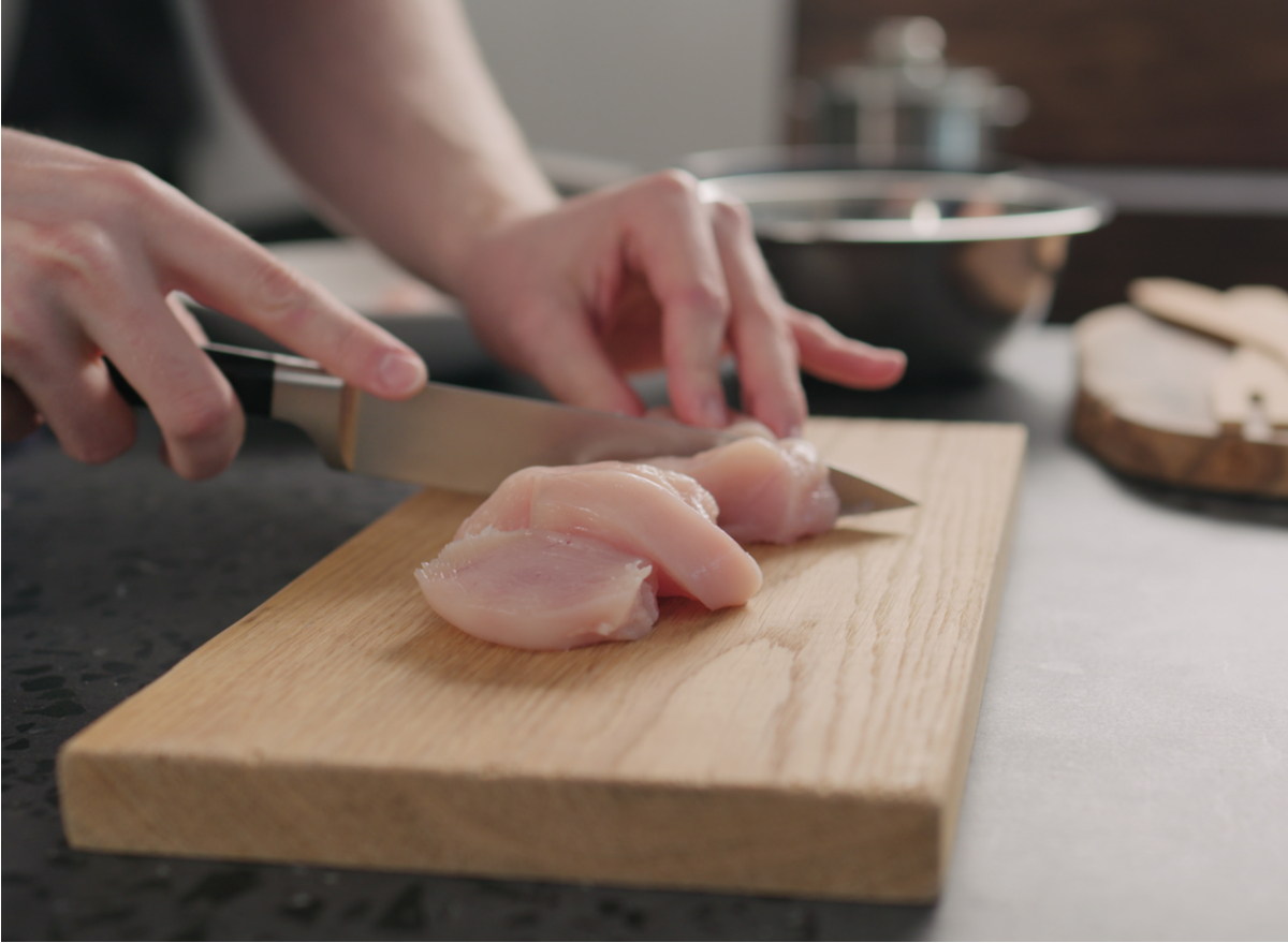 man slicing raw chicken