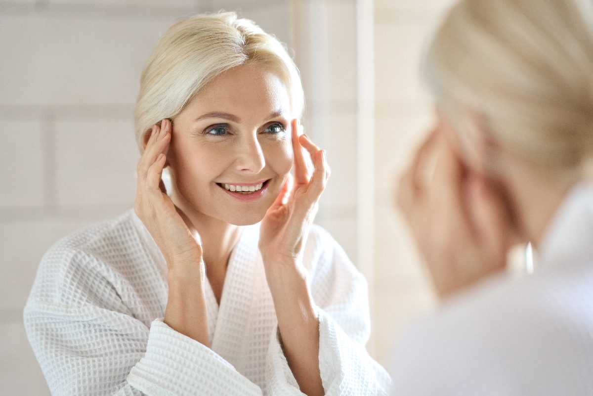 mature woman fight signs of aging with facial massage in bright bathroom