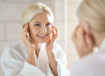 mature woman fight signs of aging with facial massage in bright bathroom