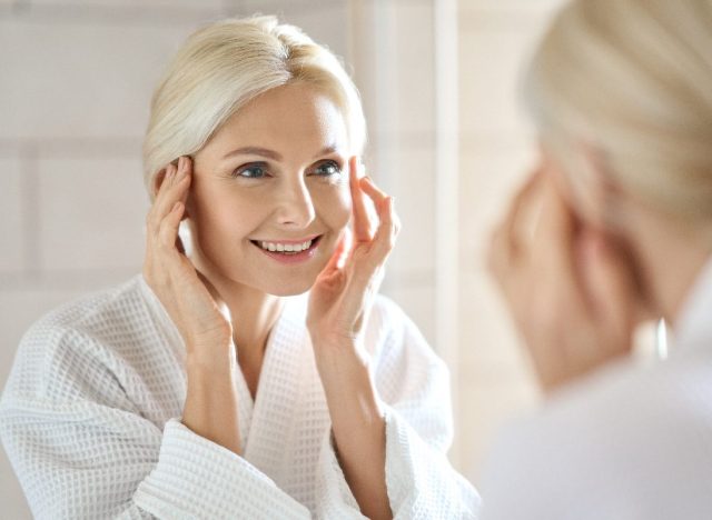 mature woman fight signs of aging with facial massage in bright bathroom