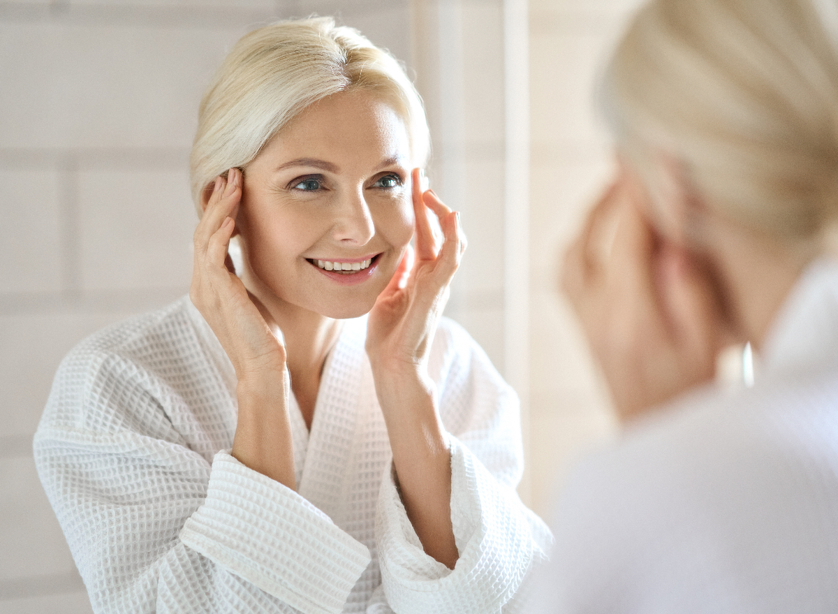 mature woman fight signs of aging with facial massage in bright bathroom