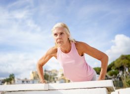 mature woman doing pushups outdoors to get rid of chicken wings