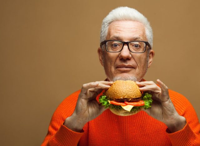 older man eating burger