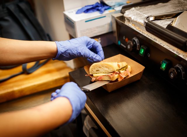 person making sandwich wearing blue gloves