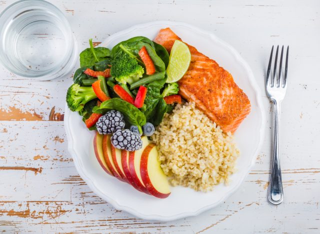 portioned dish with fish, cereals, vegetables, fruits and a glass of water
