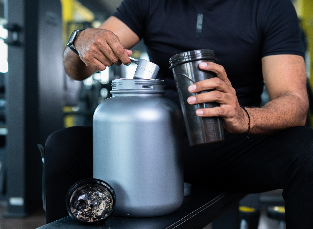 man making protein powder shake at the gym