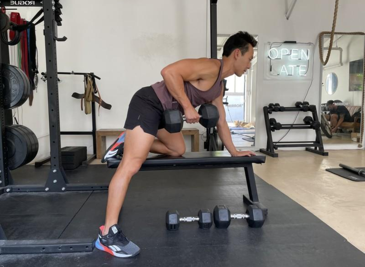 trainer performing dumbbell row, exercise to get rid of a pot belly