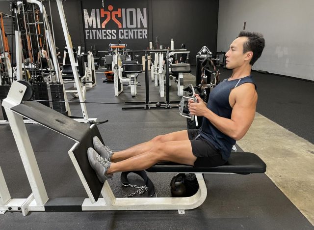 trainer demonstrating seated row to blast your beer gut