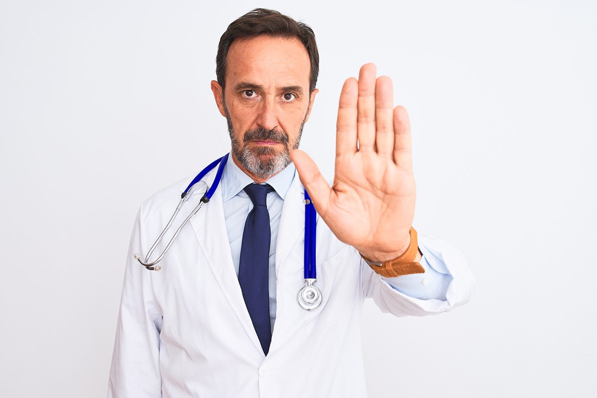 Middle,Age,Doctor,Man,Wearing,Coat,And,Stethoscope,Standing,Over