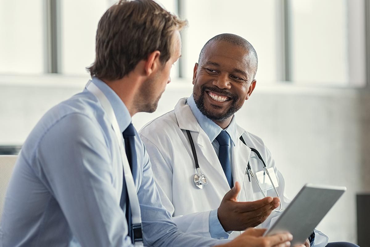 Two,Mature,Smiling,Doctors,Having,Discussion,About,Patient,Diagnosis,,Holding