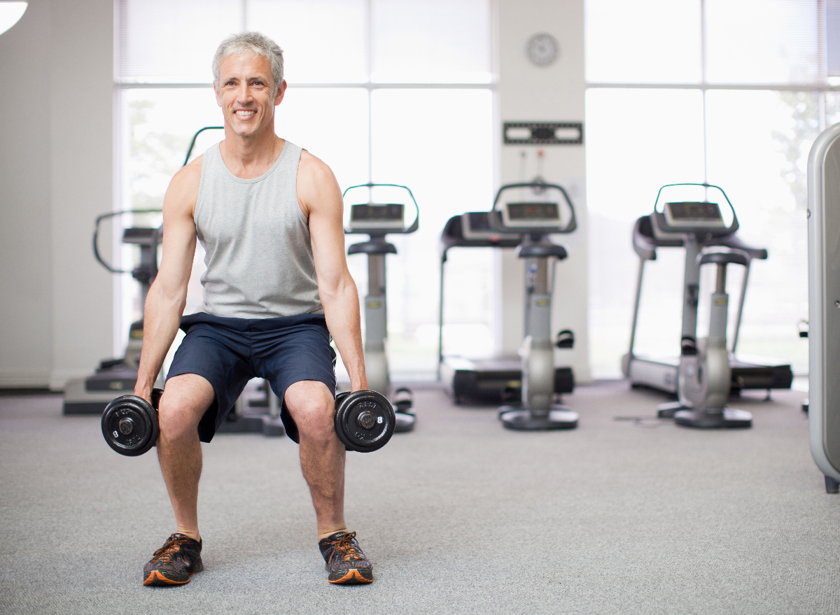 man in his 50s doing squats with dumbbells to get rid of a pot belly