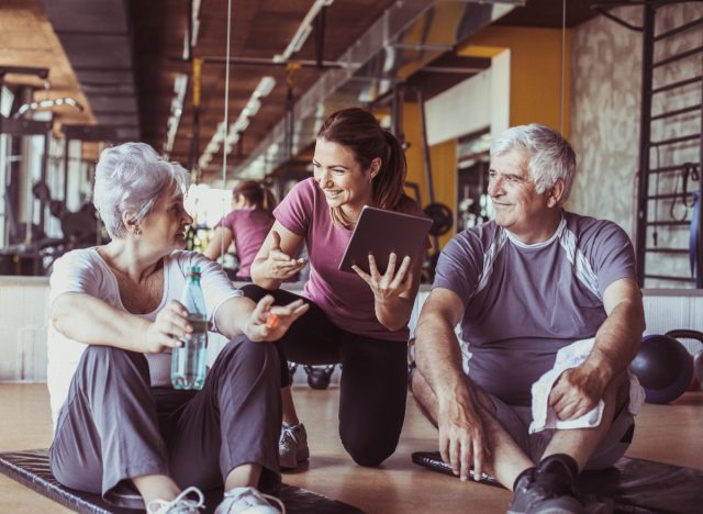 consultation d'un entraîneur avec un couple d'âge mûr discutant des meilleurs exercices pour les personnes âgées