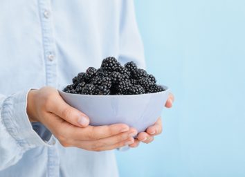 woman holding bowl of blackberries