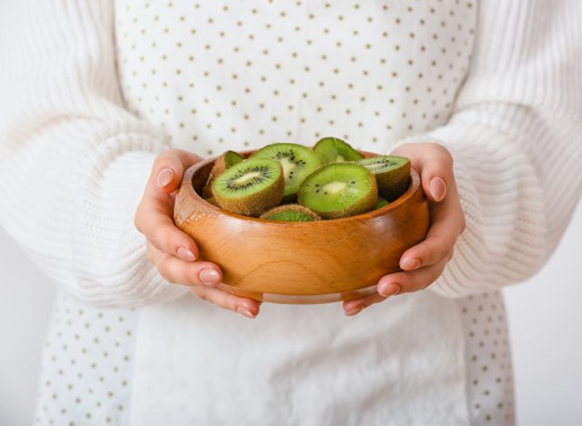 woman holding bowl of kiwis