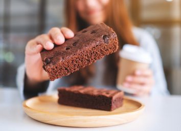 woman holding coffee and grabbing brownie