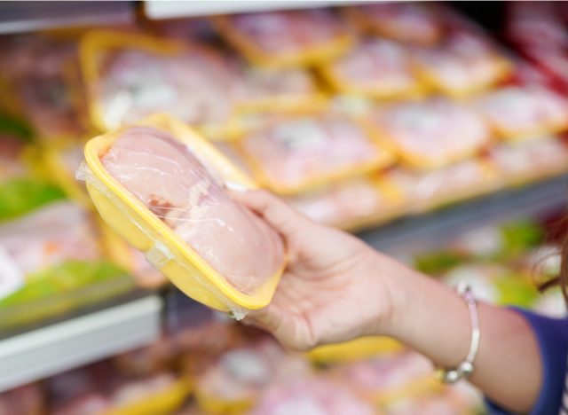 woman holding packaged raw chicken