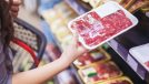 woman holding wrapped meat at grocery store