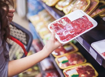 woman holding wrapped meat at grocery store