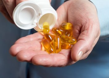 woman pouring omega 3 supplements into hands