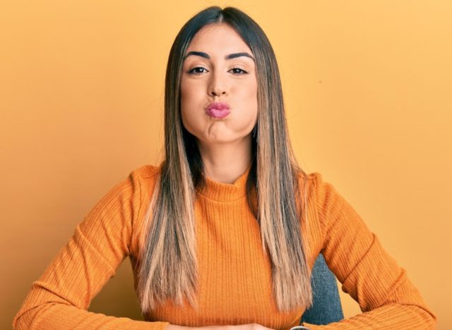 woman doing pufferfish face jowl exercises