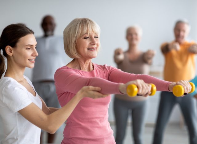 trainer and mature woman doing exercises for seniors