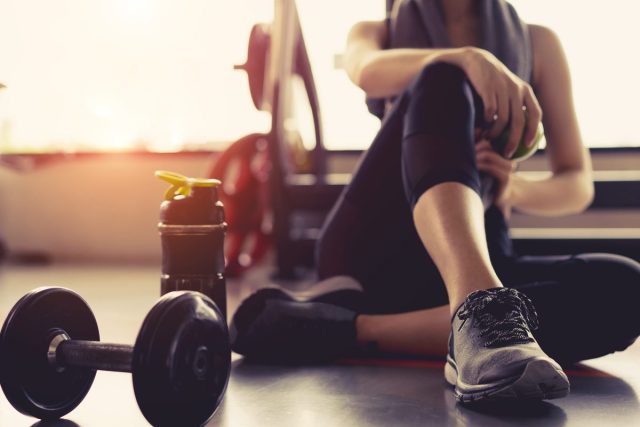 woman sitting in gym with weight and water bottle