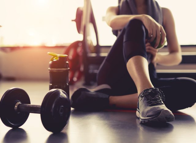 woman sitting in gym with weight and water bottle