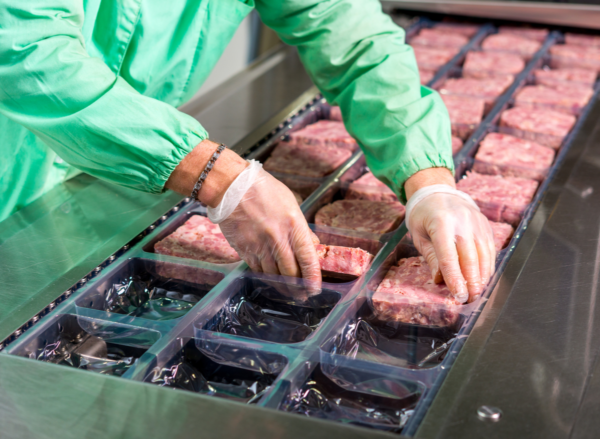 worker putting raw meat into package