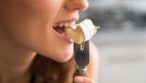 Woman biting into cheese on fork