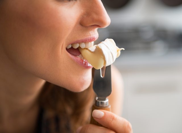 Woman biting into cheese on fork