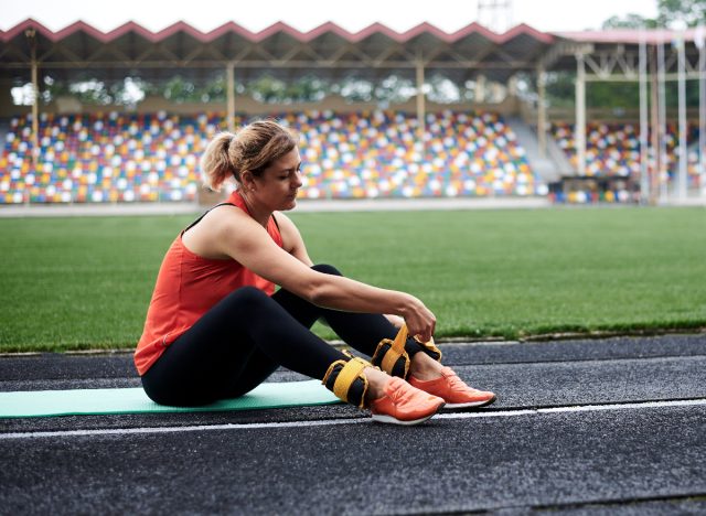 woman strapping ankle weights for cardio to get rid of sagging lower belly