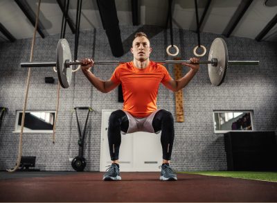 man doing barbell back squat to get a toned belly in 1 week