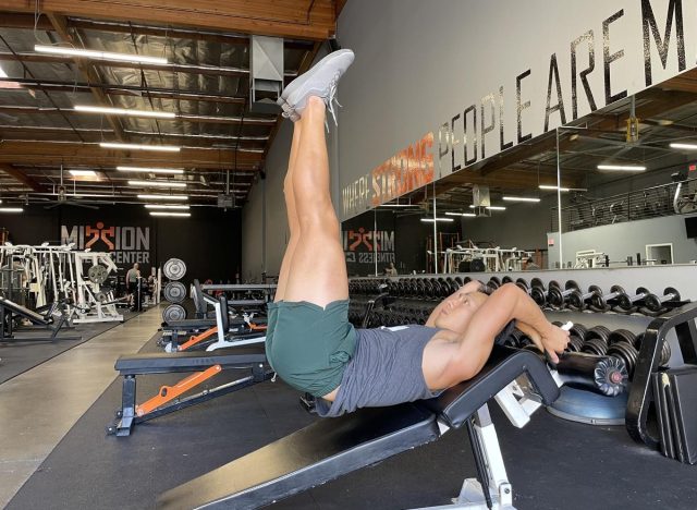 trainer doing leg raise on decline bench