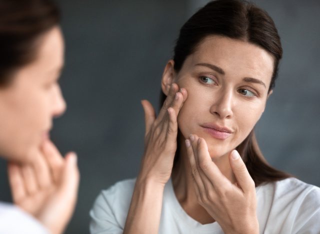 concerned woman looking in mirror subtle red flags of skin cancer