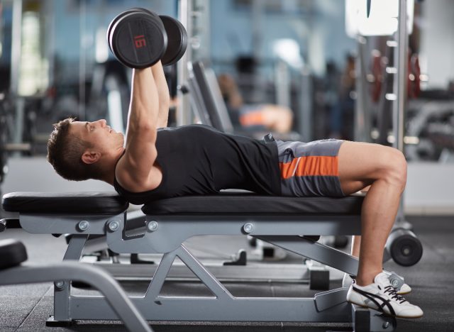 man demonstrating dumbbell bench press to blast your beer gut