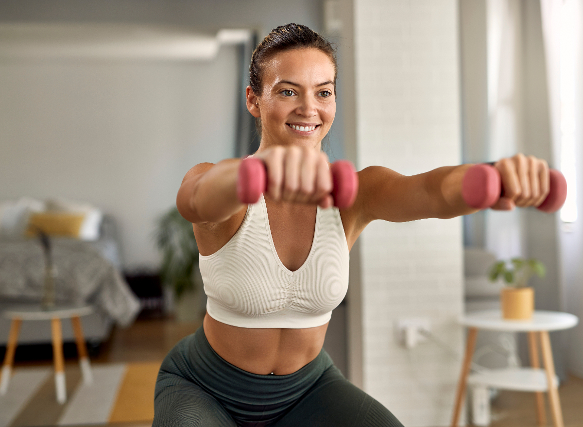 fit woman doing hourglass body workout at home, bright living room