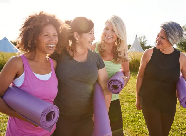 friends holding yoga mats walking to outdoor yoga class