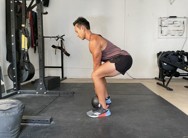 trainer demonstrating a kettlebell deadlift to reduce your belly