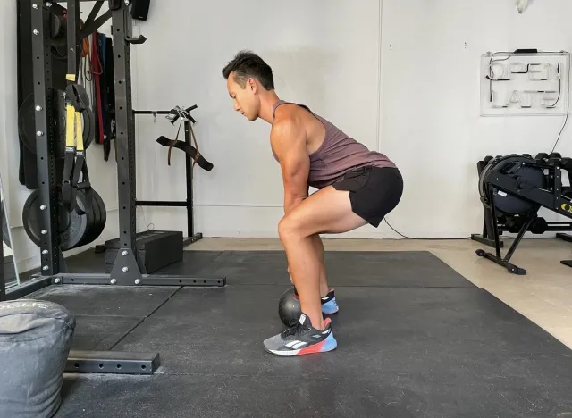 trainer demonstrating kettlebell deadlift to shrink your belly