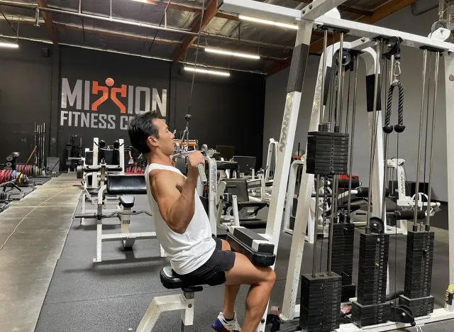 trainer doing lat pulldown to demonstrate exercise tricks to slow down aging