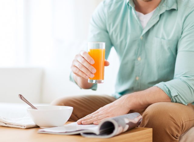 man reading a magazine and holding orange juice