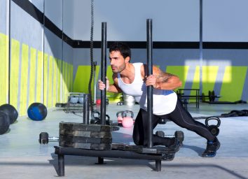 man doing sled push to shrink a big belly for good