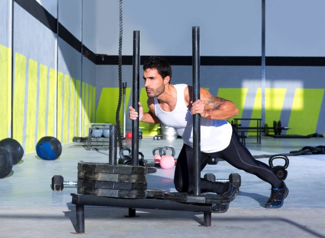 man doing sled push to shrink a big belly for good