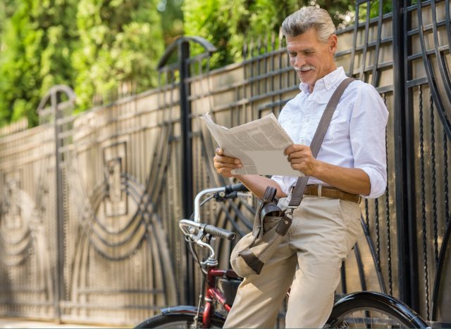 mature man sitting on bike reading newspaper, keep your brain young