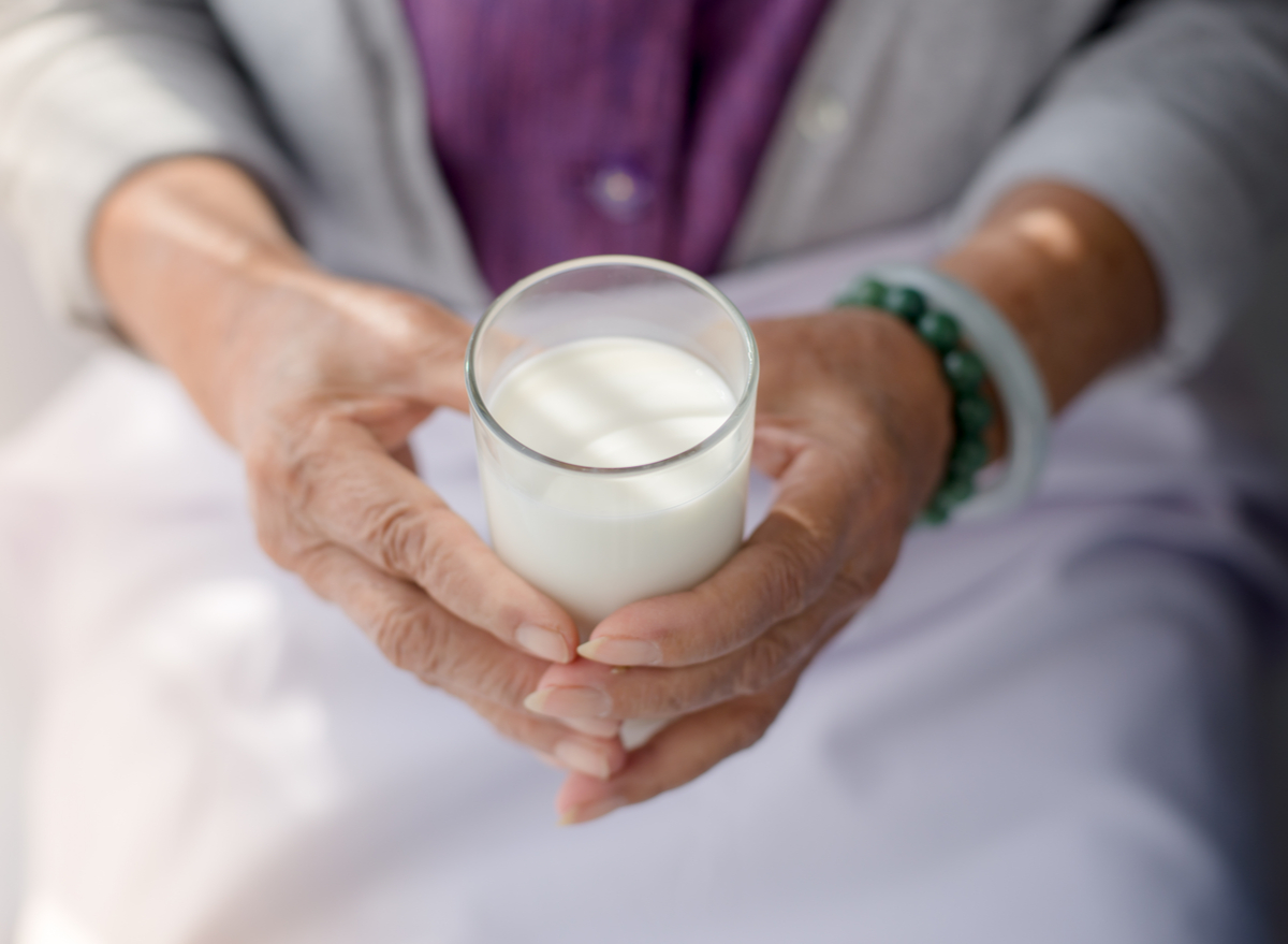 older woman holding glass of milk