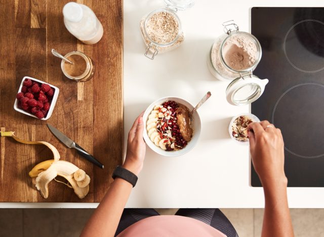 fit woman preparing peanut butter smoothie bowl, representing best time to eat after a workout