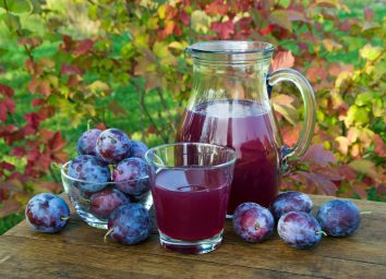prune juice in a carafe and glass with plums