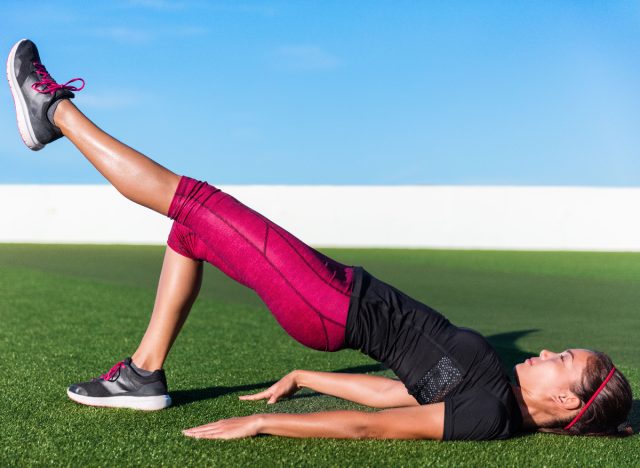 woman performing single-leg glute bridge on turf