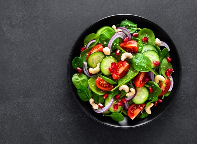 spinach salad with cucumbers, tomatoes, onions, and cashews