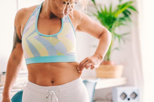 A woman demonstrates the concept of reducing your gut after 40 workouts